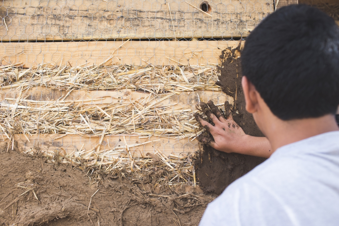 Sergio Campos '26 spreads superadobe mixture onto walls.