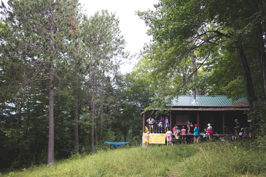 Students sit outside a cabin