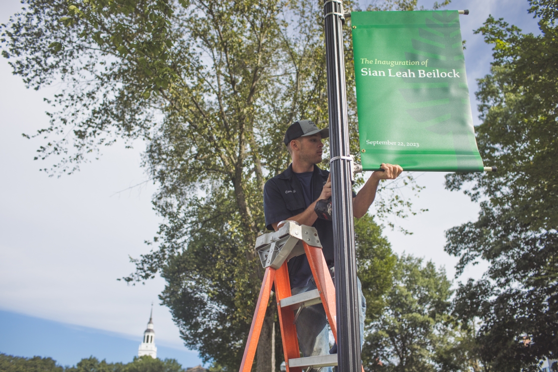 Cam Blossom of FO&amp;M fits an inauguration banner to a light post.