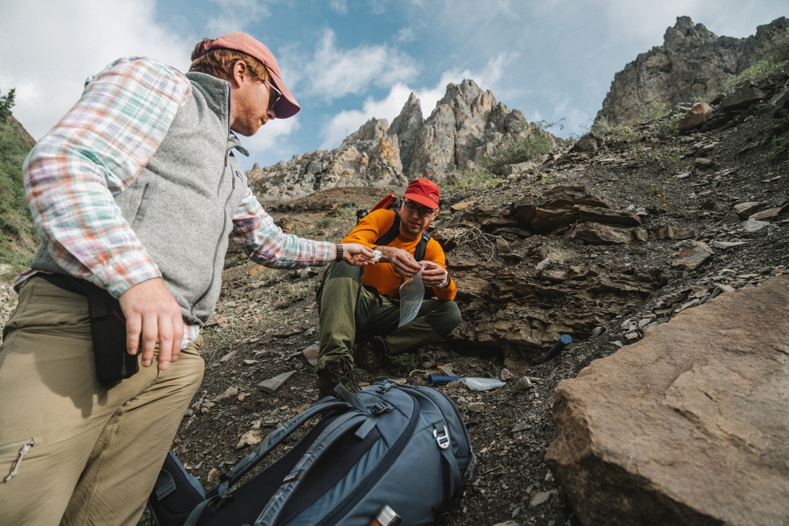 Two researchers bag fossils samples in shale