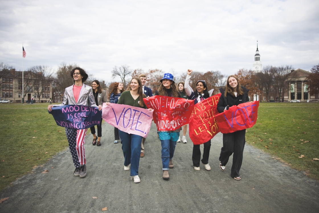 Dartmouth students holding voting signs walking across the Dartmouth Green