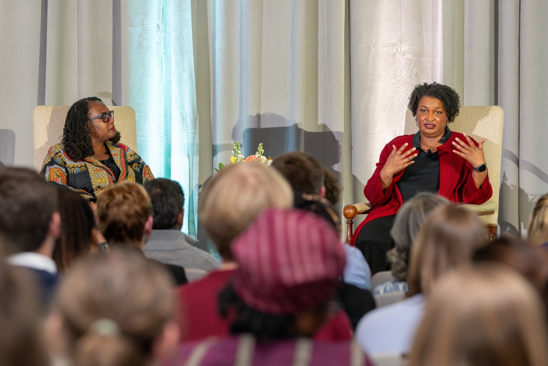 Shontay Delalue and Stacey Abrams sitting together for a fireside chat