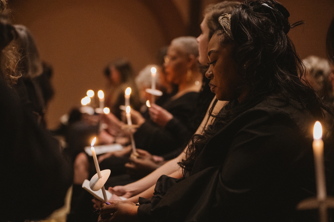 Attendees of the celebration silently sitting together with candles lit in remembrance