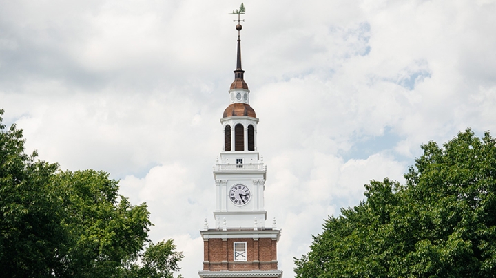 the top of Baker tower surrounded by green trees with white clouds in the background
