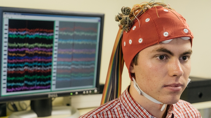 a research assistant wearing a red cap with wires connected to it