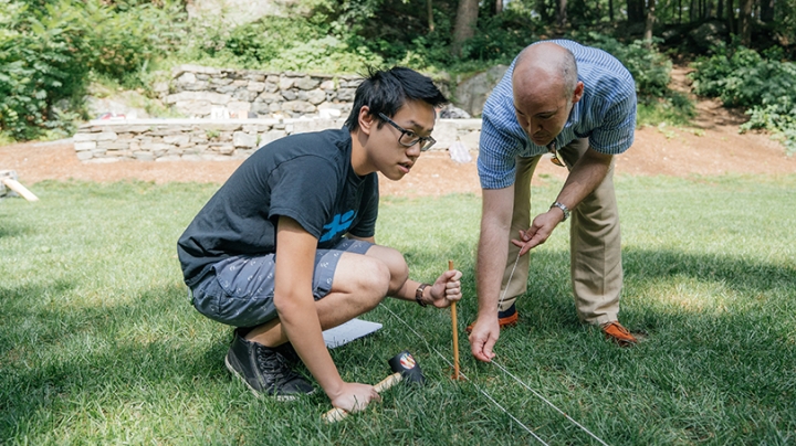 a student and professor placing string on the ground