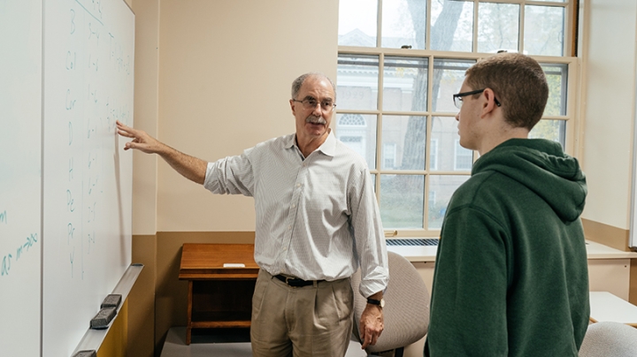 Phil Hanlon ’77 standing with a student at a white board