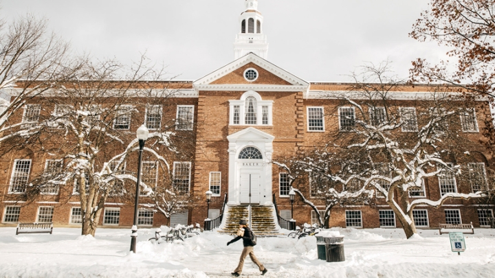 A student walks on the sidewalk in front of Baker-Berry Library
