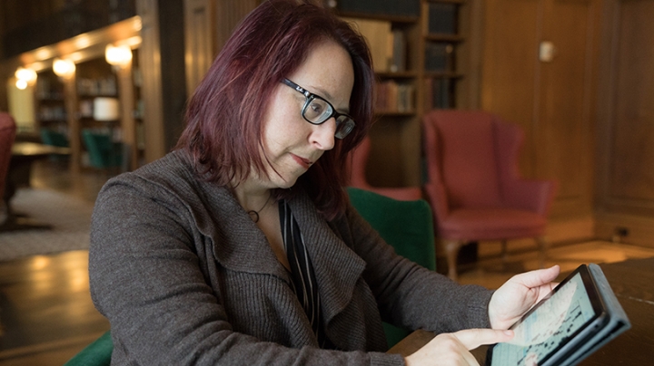 Laura Braunstein touching her finger to a tablet with a crossword puzzle on the screen