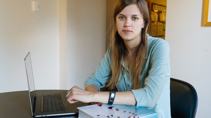 Margaret Lawson sitting at a table with her laptop and a copy of her mentor's textbook