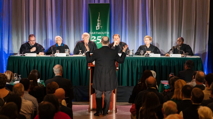 Gregory Garre ’87 standing at a podium in front of a panel of distinguished alumni jurists