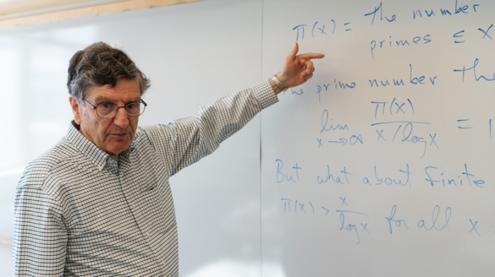 Mathematics professor emeritus Carl Pomerance points to a whiteboard
