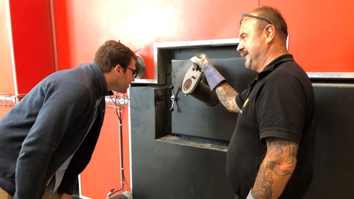 At the St. Merlose Heating Plant in Holbaek, Denmark, the plan manager, right, shows Peter Cahill, Tuck '20, combustion in a hot water boiler. The biomass facility annually burns 3,000 tons of straw, grown by area farmers, and delivers heat to 400 custome