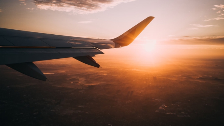 Airplane wing from a plane's window with the sun setting