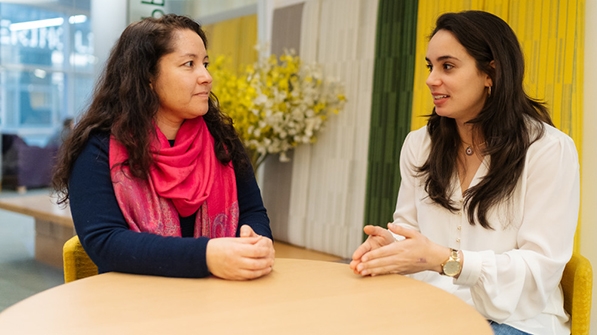 Alicia Brandon and a student sitting at a table and talking