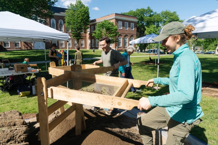 Josh Wende ’19 and Katie Hoover ’22 screen soil at an archeological excavation site in front of Dartmouth Library’s Baker-Berry Library.