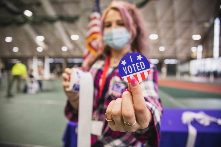 A polling-station volunteer with an 'I Voted' sticker