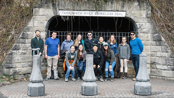 a group of students standing outside the gated entrance of a coal mine